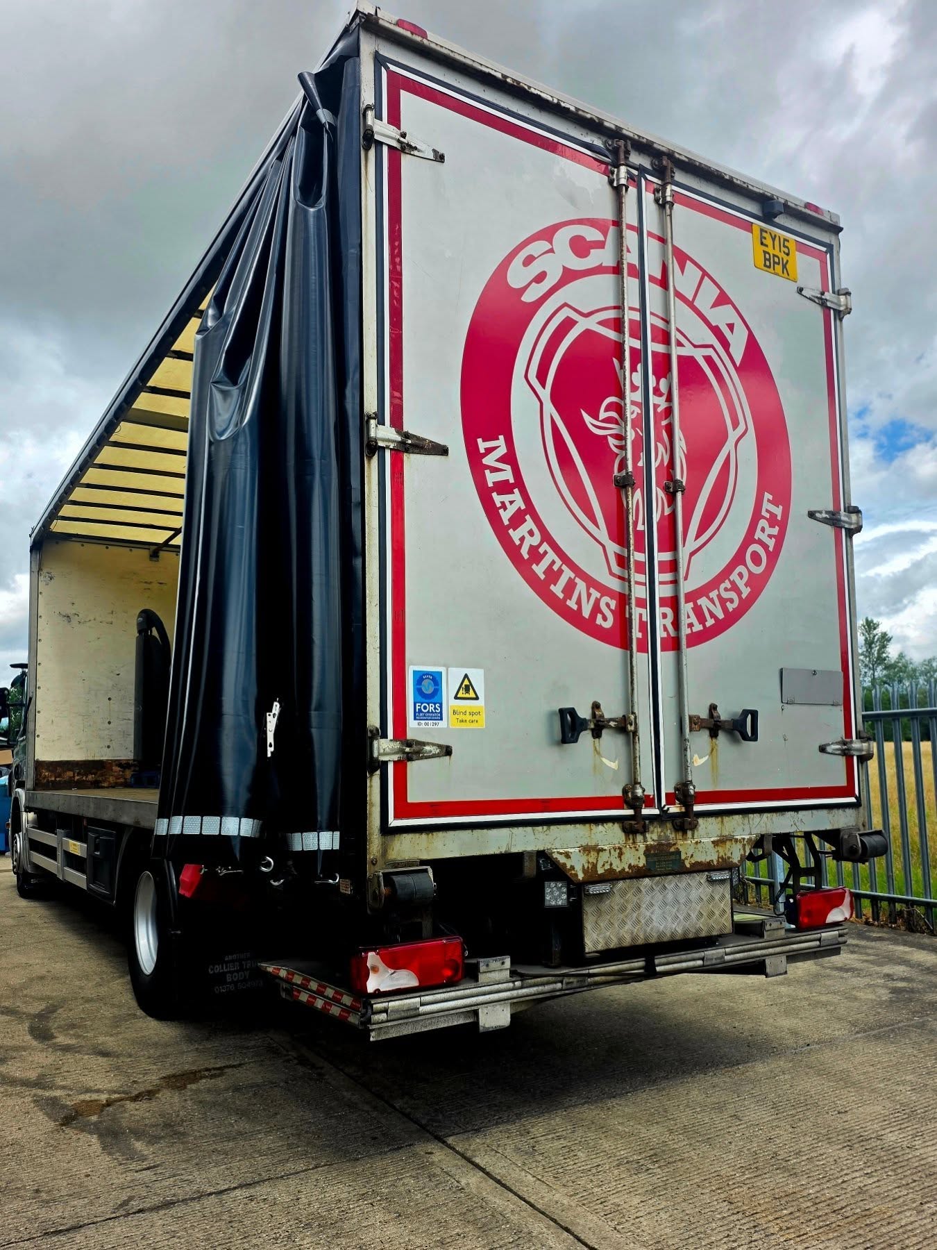 Rear view of a Martins Transport vehicle with branded livery and open curtain side